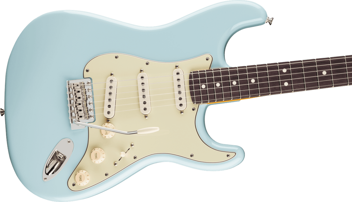 Angled view of the Daphne Blue Stratocaster body: master volume and two tone knobs, five-way blade switch, aged-white pickup covers and the chrome six-saddle tremolo