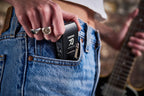 Boss Katana GO (KTNGO2) being slipped into a jeans pocket with the plug folded flat, showing how small the amp is