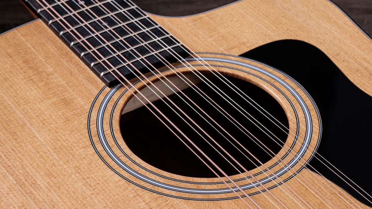 Twelve strings running over the soundhole and multi-ring rosette of the Taylor 150ce